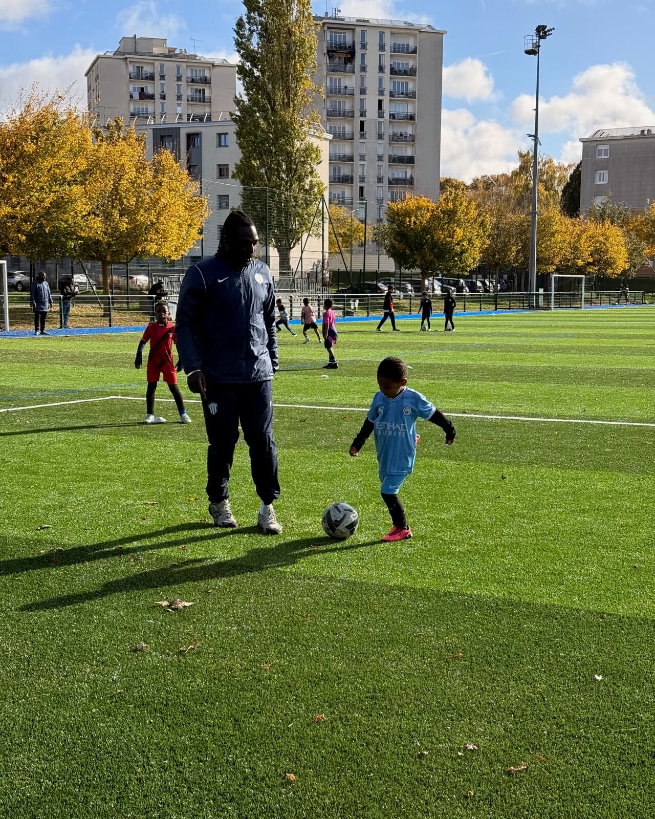 Un coach accompagne un jeune joueur balle au pied